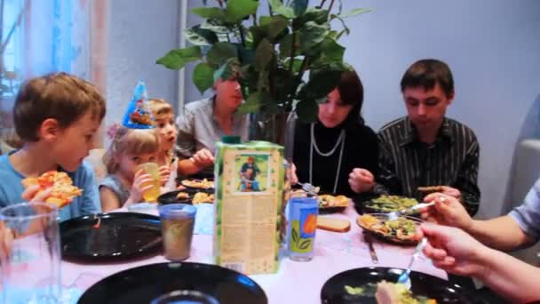 Famiglia e molti bambini con ospiti si siedono intorno al tavolo, festeggiando la festa di compleanno — Video Stock