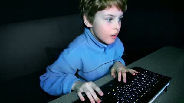 Menino joga videogame em tela grande com teclado — Vídeo de Stock