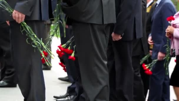 Människor stiger på trappan med röda blommor, bara ben syns — Stockvideo