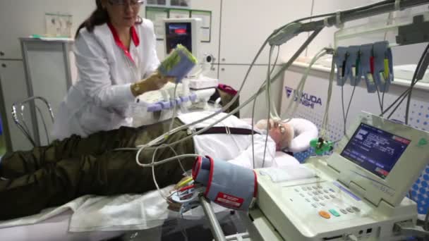 Nurse caring for elderly man among medical equipment at medical exhibition Zdravookhraneniye2010 — Stock Video
