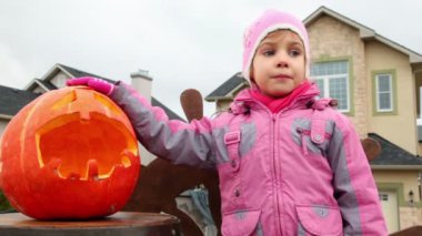 Little girl chewes candy, pumpkin of Halloween