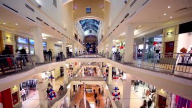 People walk along boutiques on multiple floors shopping center Atrium