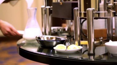 Woman came and put milk vessel on plate at coffe table
