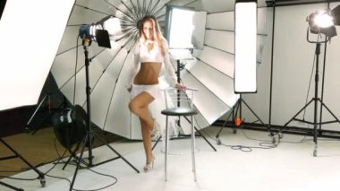 Genç model fotoğraf stüdyosu içinde sandalye etrafında yürüyüş