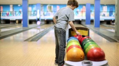 küçük çocuk bowling topu alıyor ve skittles yenmek için atar