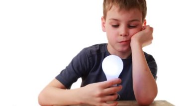 Boy holds in hand light bulb that miraculously lights, he is astonished