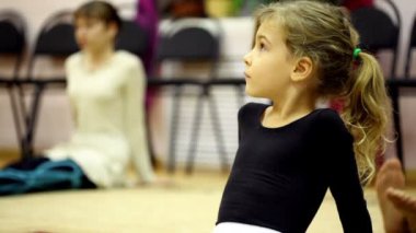 Little girl dressed in ballet clothes sit on floor