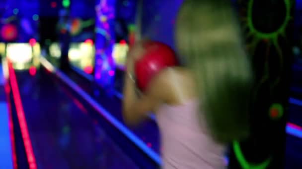 Meisje staat en glimlacht met bowling bal en vervolgens gooit het om te verslaan kegelen — Stockvideo
