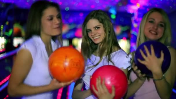tři dívky stojí s bowlingové koule a pak hodit ji porazit kuželky