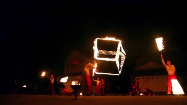 Drei Männer drehen brennende Gegenstände und Mädchen kommen und kreisen Feuerwerk — Stockvideo