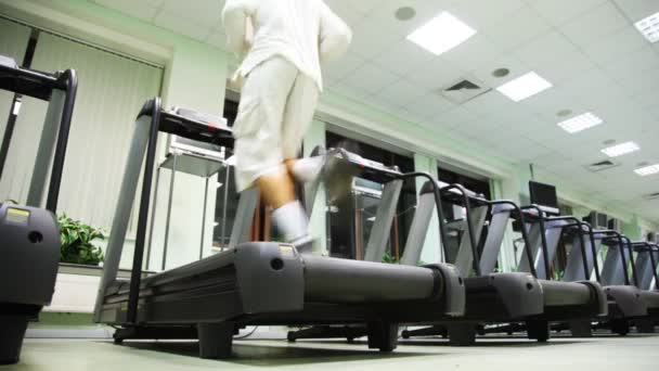 Man loopt snel op één van de vele loopband in grote fitnessruimte — Stockvideo
