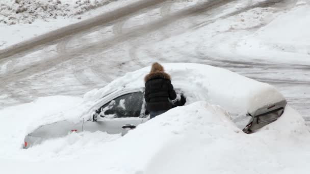 女性は雪だらけの車を掘る — ストック動画