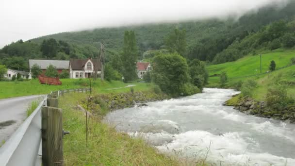 Schneller Fluss fließt durch kleines Dorf in den Bergen — Stockvideo