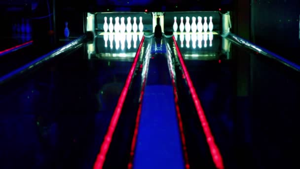 Two bowling lanes lit in dark club, bolls roll and beat tenpins — Stock Video