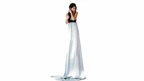 Niezwykle wysoka brunetka modelu w długiej sukni koryguje fryzurę na białym tle — Wideo stockowe