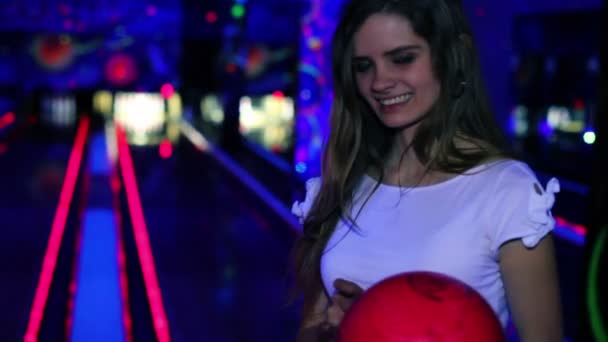 Chica se para de lado y sonríe con bola de bolos en las manos en el club — Vídeos de Stock