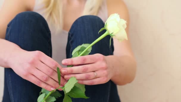 Jovencita se sienta en el suelo y sostiene rosa — Vídeo de stock