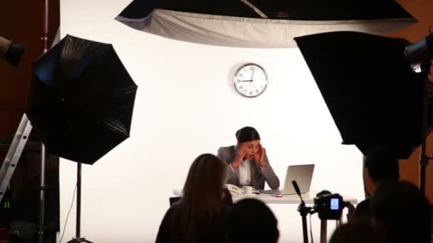 El modelo se sienta a la mesa con el portátil a la demostración del rodaje del estudio — Vídeo de stock