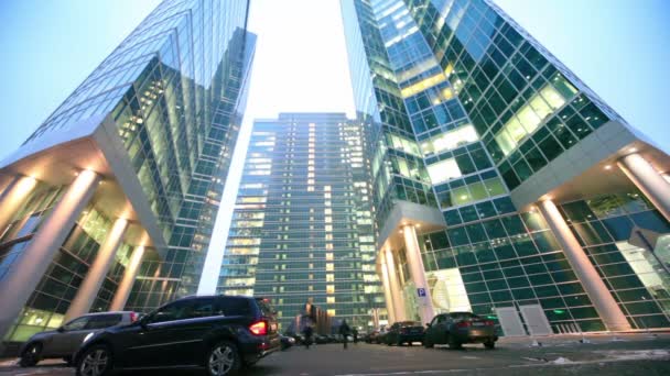 Cars drive up to parking in front of three skyscrapers — Stock Video