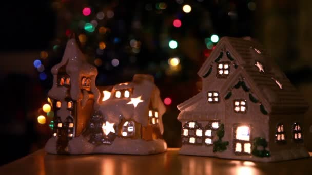 Dois brinquedo casa-castiçal stand no fundo de enfeites de árvore de natal — Vídeo de Stock