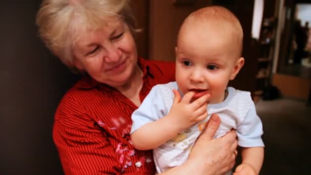 Grootmoeder houden baby in handen en glimlachen — Stockvideo