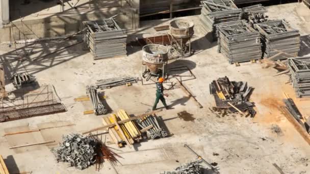 Travailleur va sur le chantier parmi les matériaux de construction — Video