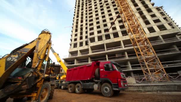 Planierraupe verlädt LKW auf Baustelle von Wohnhaus — Stockvideo