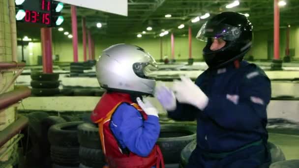 Carting entrenador ayuda a niño pequeño a ponerse el casco — Vídeo de stock