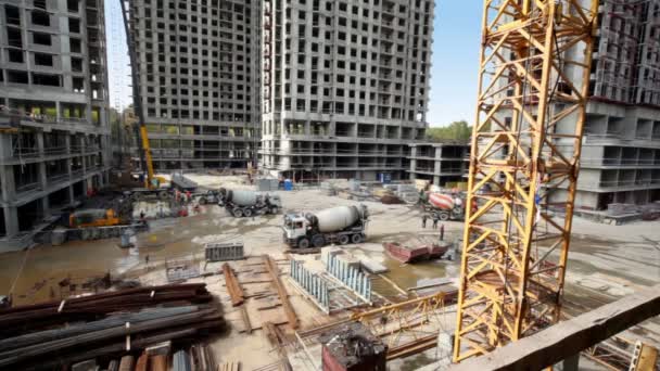 Рабочие и бетономешалки на строительной площадке многих домов — стоковое видео