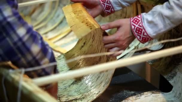 Two men dressed in national costumes laid sheets of birch bark — Stock Video