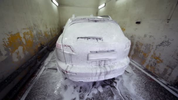 Automobile stand in soap suds inside narrow car wash garage — Stock Video