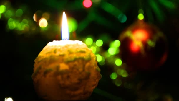 Candle lit in front of festive lights Christmas tree — Stock Video