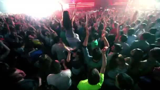 Menina senta-se nos ombros dos homens entre as pessoas na festa rave, DJ Armin Van Buuren no palco — Vídeo de Stock