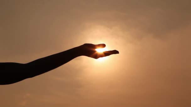 La silueta de la mano sostiene el sol en la palma de la mano, comprime y abre la palma en el puño — Vídeos de Stock