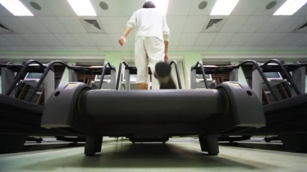 El hombre va en la cinta de correr en el gimnasio vacío grande — Vídeo de stock