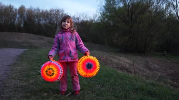 Liten flicka håller och höja två bollar från papper på natten — Stockvideo