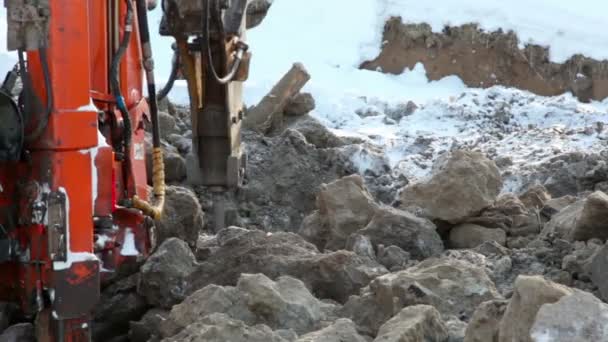 Máquina aburrida rocas terrestres en invierno, montón de tierra a su lado — Vídeos de Stock