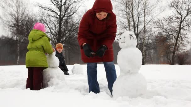Μητέρα κάνει τα χέρια για χιονάνθρωπος με δύο παιδιά — Αρχείο Βίντεο