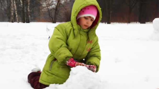 Menina jogar com neve e fazer boneco de neve — Vídeo de Stock