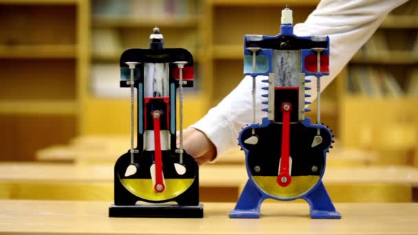 Mennesket roterer hver av to modeller av forbrenningsmotor på skrivebordet – stockvideo