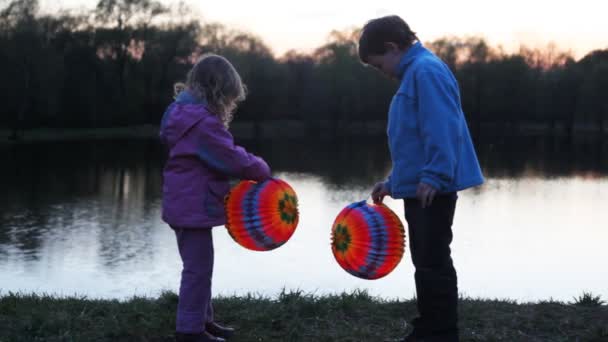 男の子と女の子が夜に紙からカラフルなボールを保持します。 — ストック動画