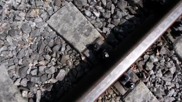 Rails en cross banden van spoorlijn onder stenen, getoond in beweging — Stockvideo