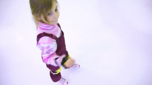 Petite fille patine sur la glace vers le bord de la patinoire — Video