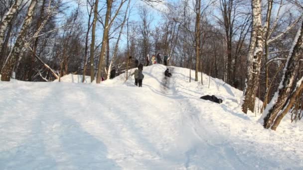 Boy slid down slope and rolled over, several people stand on hill — Stock Video