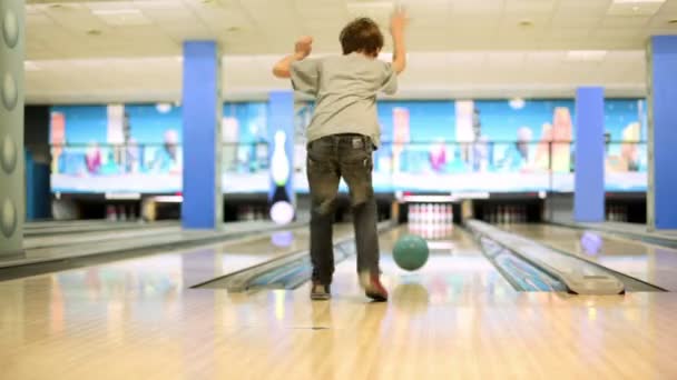 Malý chlapec vyvolá bowlingovou kouli porazit kuželky, pohled zezadu — Stock video