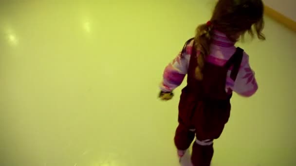 Niña patina en pista de hielo, destellos de luz de colores — Vídeo de stock
