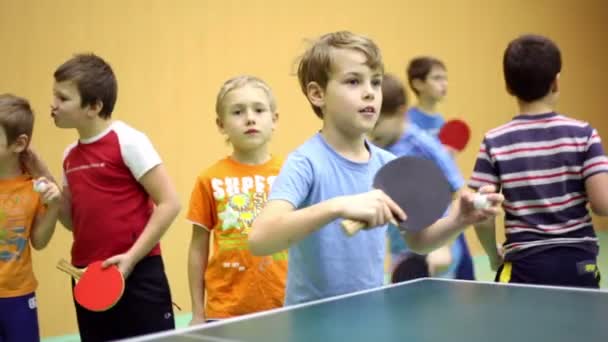 Little boy playing ping pong, second kid stands behind and repeats movements — Stock Video