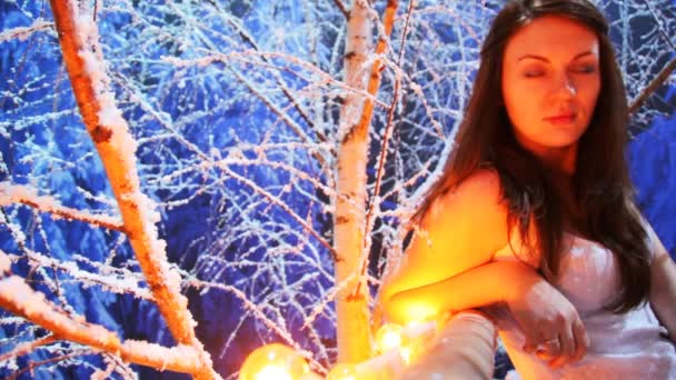 Chica se sienta en balcón iluminado en el bosque de abedul nevado por la noche — Vídeos de Stock