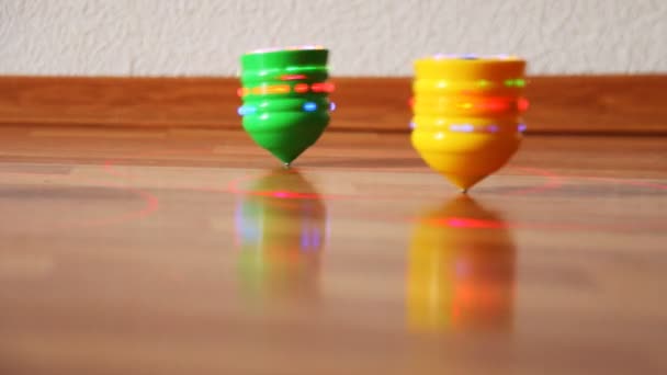 Toy tops with bright lights roll on table upside down — Stock Video
