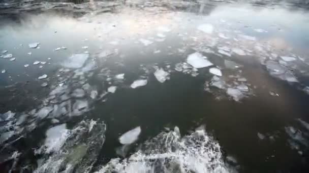 Segeln Sie durch Eis im Fluss, der den Wald am Ufer widerspiegelt — Stockvideo